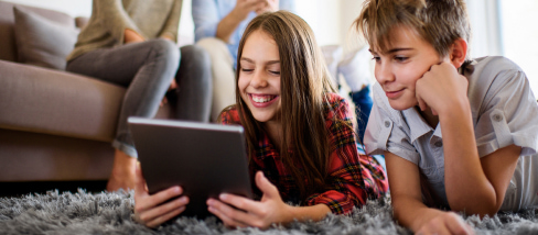 Deux enfants allongés regardant une tablette